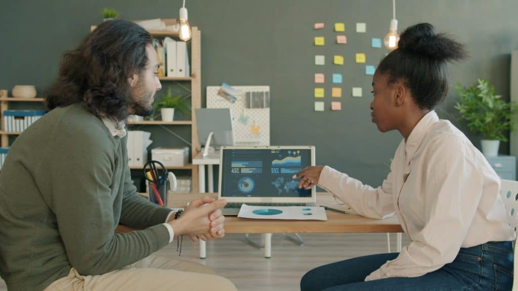 Google Analytics expert reviewing GA4 data with a client on a laptop